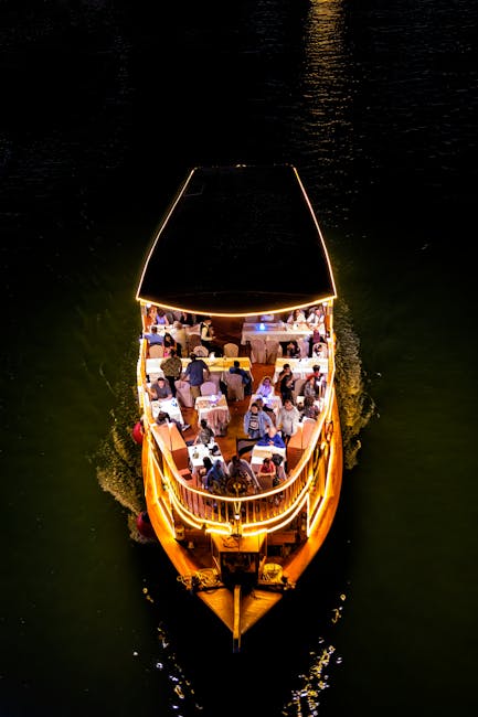 A stunning aerial view of a night cruise boat with illuminated deck and passengers enjoying the ride.
