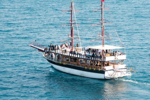 Aerial view of a double-decker tourist boat cruising on the open sea, vibrant and lively.