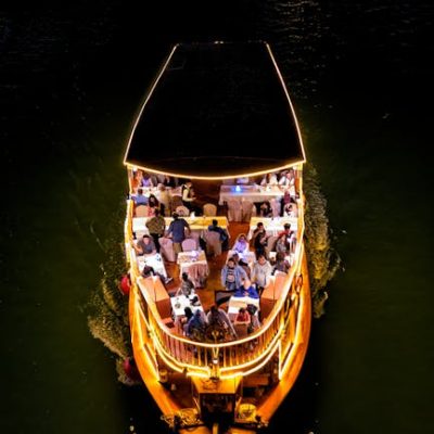 A stunning aerial view of a night cruise boat with illuminated deck and passengers enjoying the ride.
